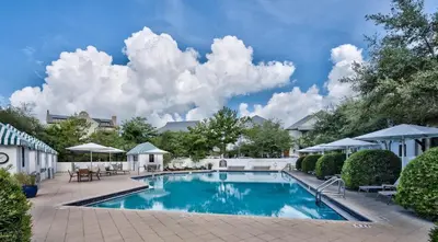 a swimming pool in a yard with chairs and umbrellas at Thyme & Place in Rosemary Beach