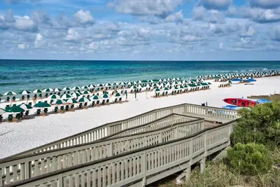 a beach with many umbrellas and the ocean at Uncorked Carriage House in Rosemary Beach