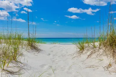 a beach with grass and the ocean in the background at Beachfront Bliss Awaits: 2-Bed, 2-Bath Condo at Sterling Reef - Sleeps 6! in Panama City Beach