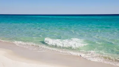 a wave breaking on a beach next to the ocean at Shores of Panama 1217 | Emerald Beach Retreat in Panama City Beach