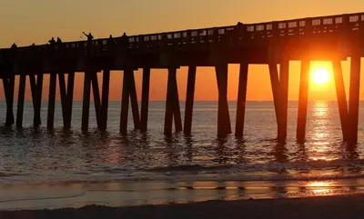 a pier with people on it at sunset at Emerald Beach 1935 in Panama City Beach
