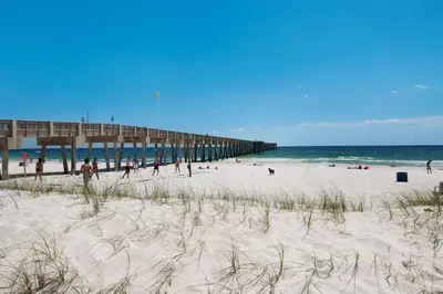 a beach with a pier and people on the sand at Watercrest 1110 - Sunset Haven in Panama City Beach