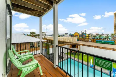a balcony with two chairs and a swimming pool at Spring Break! Heated Pool, Walk 2 Beach, Sleeps 11 in Panama City Beach