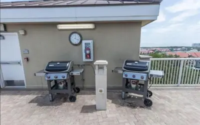 two tables on a balcony with a clock on a building at Grand Panama 407 in Panama City Beach