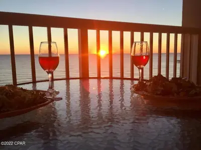 two glasses of wine on a balcony with the sunset at Calypso 1209W Corner 3BR 3BA 2 sets of beach service in Panama City Beach