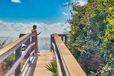 a woman looking at her cell phone on a boardwalk near the ocean at 30A Caspian Blue Carriage in Seacrest