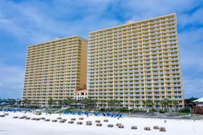 a large yellow building with chairs and a beach at Calypso 1204E in Panama City Beach