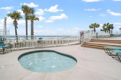 a small swimming pool with palm trees and the beach at Watercrest 1603 - 2 BR 2 BA Beachfront Balcony in Panama City Beach
