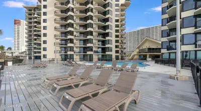 a deck with chaise lounge chairs and a building at Sunbird Resort 8th Floor Sunsets - by Sunbird Rentals in Panama City Beach