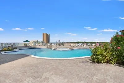 a swimming pool at a resort with a building in the background at Grand Panama by Panhandle Getaways in Panama City Beach