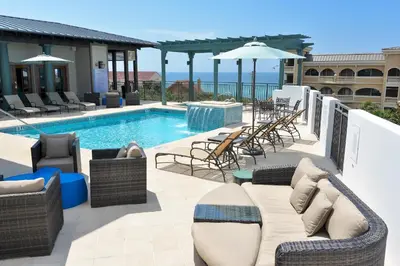 a swimming pool with wicker furniture next to a patio at WaterHouse 402 in Inlet Beach