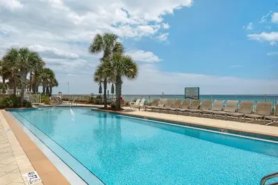 a large swimming pool with palm trees and chairs at Aqua 1905 in Panama City Beach