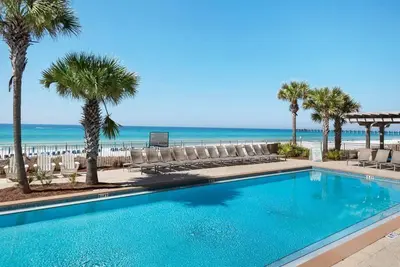 a swimming pool with chairs and the beach at Aqua 0502 in Panama City Beach