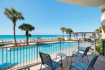a balcony with chairs and a pool and the beach at Aqua 2110 in Panama City Beach