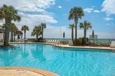 a large swimming pool with palm trees and the ocean at Aqua 0904 in Panama City Beach