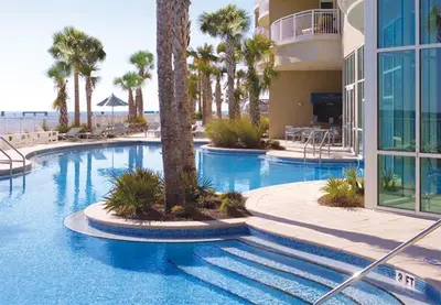 a large swimming pool with palm trees and a building at Aqua 0503 in Panama City Beach