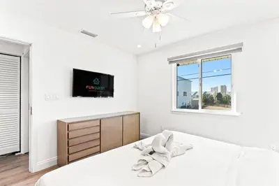 a white bedroom with a bed and a tv at Ocean Breeze 1C in Panama City Beach