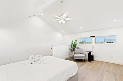 a white bedroom with a bed and a ceiling fan at Ocean Breeze 1C in Panama City Beach