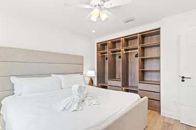 a bedroom with a white bed with a ceiling fan at Ocean Breeze 2A in Panama City Beach