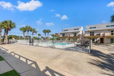 a fence in front of a pool with palm trees at Ocean Breeze 2A in Panama City Beach