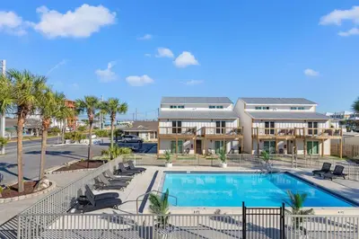 a swimming pool with chairs and a building at Ocean Breeze 2C in Panama City Beach