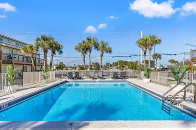 a swimming pool with chairs and palm trees at Ocean Breeze 2B in Panama City Beach