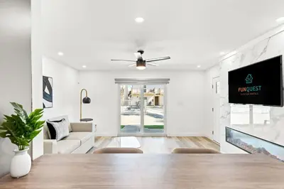 a white living room with a table and a tv at Ocean Breeze 3B in Panama City Beach