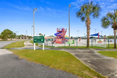 a park with a playground with a sign and palm trees at Endless Summer A36 - 