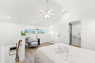 a white bedroom with a bed and a chair at Ocean Breeze 5D in Panama City Beach