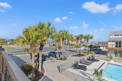 a resort with a pool and palm trees and a parking lot at Ocean Breeze 5C in Panama City Beach