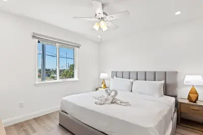 a white bedroom with a bed with a ceiling fan at Ocean Breeze 5C in Panama City Beach