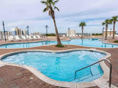a large swimming pool with a palm tree and chairs at Laketown Wharf #1137 in Panama City Beach