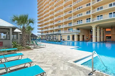 a hotel swimming pool with blue benches in front of a building at Calypso 3-2007 by Emerald Coast Retreats in Panama City Beach