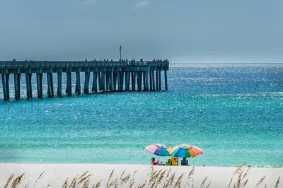 two people under umbrellas on a beach near a pier at Calypso 3-2007 by Emerald Coast Retreats in Panama City Beach