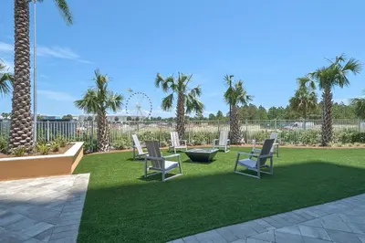 a lawn with chairs and palm trees in a yard at Calypso 3-2112 by Emerald Coast Retreats in Panama City Beach
