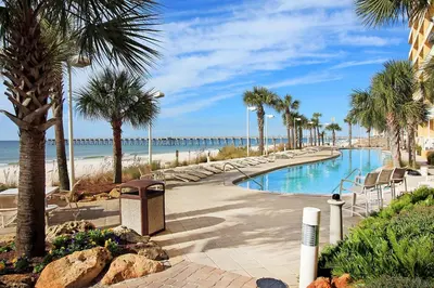 a swimming pool with palm trees and a beach at Calypso 3-2112 by Emerald Coast Retreats in Panama City Beach