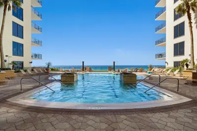 a swimming pool in a resort with the ocean in the background at Origin 0427 - One Bedroom - Partial Gulf View by Beach Haven Vacation Rentals in Panama City Beach