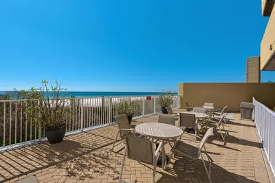 a patio with tables and chairs and the beach at Emerald Isle 403 by Emerald Coast Retreats in Panama City Beach