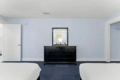 a bedroom with two beds and a dresser with a mirror at Sharkys Retreat 701 by Beach Haven Vacation Rentals in Panama City Beach