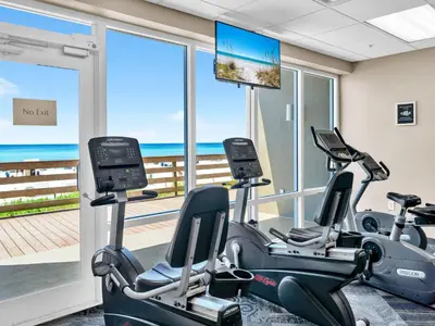 a gym with cardio machines and a view of the ocean at Tidewater 1406 in Panama City Beach
