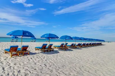 a row of blue umbrellas and chairs on a beach at Edgewater Tower 1-608 in Panama City Beach