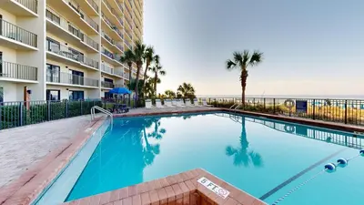 a swimming pool in front of a building with the ocean at Commodore 0502 in Panama City Beach