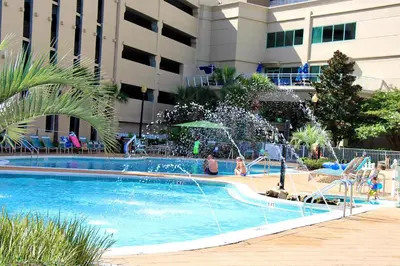 a swimming pool with a fountain in front of a building at Emerald Beach 1130 in Panama City Beach
