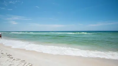 a beach with people walking on the sand and the ocean at Hidden Beach 201 in Santa Rosa Beach
