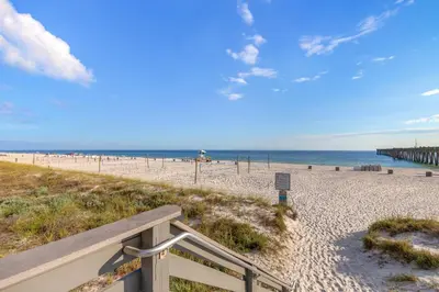 a sandy beach with a bench and the ocean at Spacious 6BR Beach Home Sleeps 15 – Relax & Reconnect at Coastal Breeze in Panama City Beach