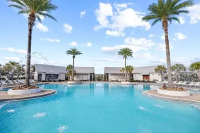 a large swimming pool with palm trees in a resort at The Tipsy Turtle in Inlet Beach