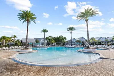 a large swimming pool with palm trees in a resort at Sunset Key in Inlet Beach