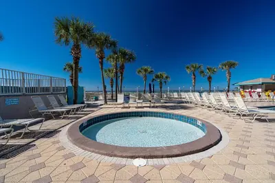 a pool with chairs and palm trees on a beach at Mariners Retreat - High Rise Beach Living in PCB in Panama City Beach