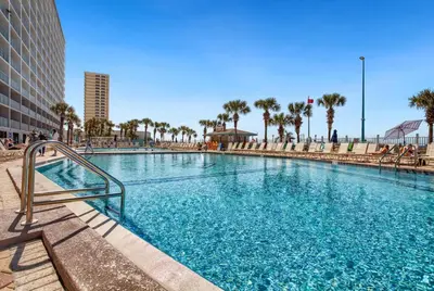 a swimming pool in a resort with palm trees at Beach Bliss Family Beachfront Living in Panama City Beach