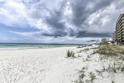a white beach with the ocean and buildings at Steps to the Beach PCB Condo with Balcony! in Panama City Beach
